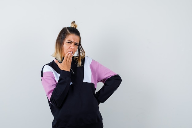 Wonderful lady holding hand on mouth in sweatshirt and looking shocked.