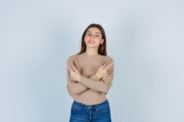 Wonderful lady in sweater, jeans pointing up while smiling and looking joyous , front view.