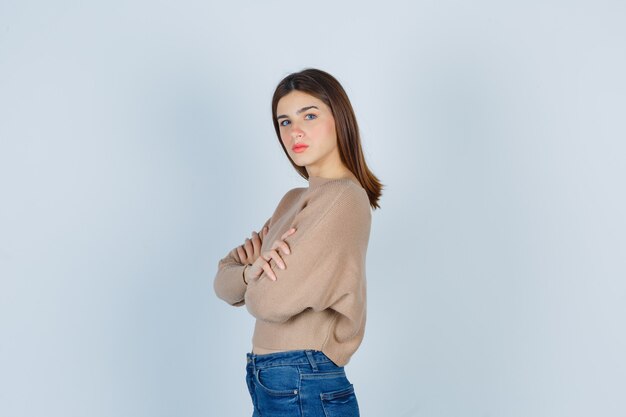 Wonderful lady with hands crossed in sweater, jeans and looking serious. .