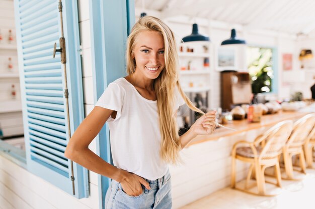 Wonderful lightly-tanned woman in retro jeans posing with positive smile.