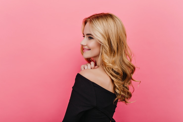 Free Photo wonderful pale girl with elegant curly hairstyle looking away. shot from back of pleased fair-haired woman in black clothes.