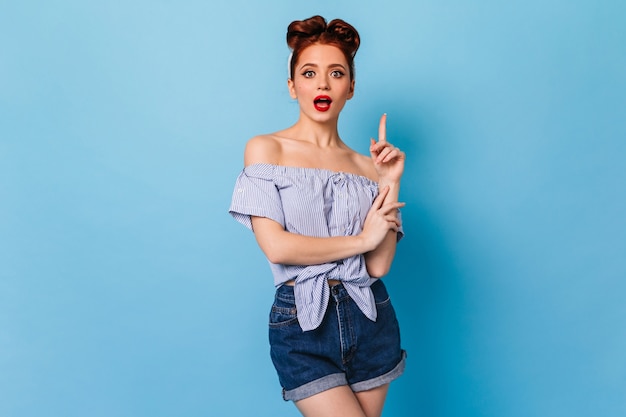 Wonderful pinup girl has idea. Studio shot of amazing ginger young woman isolated on blue space.