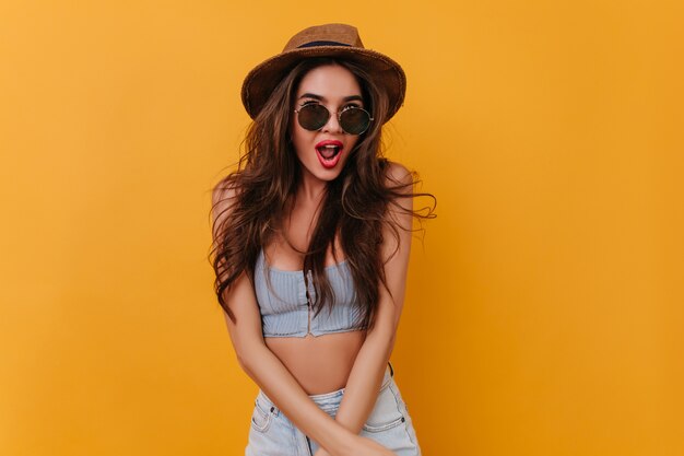 Wonderful sensual girl in glasses posing with surprised smile on yellow space