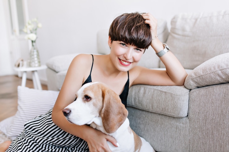 無料Photo ビーグル犬との面白いゲームの後に家でポーズをとる手で頭を支える素晴らしい日焼けした女の子