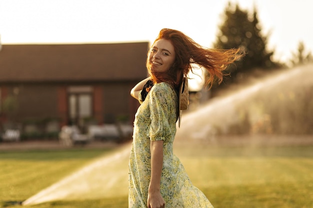 Free photo wonderful woman with long red hair stylish hat and bandage on neck in green charming clothes smiling and looking into camera outdoor