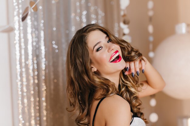 Wonderful young white lady with shiny dark hair posing with pleasure at christmas party. Lovable caucasian woman expressing happiness during photoshoot at event.