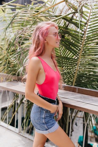 Wonderful young woman in stylish summer outfit posing on exotic background.