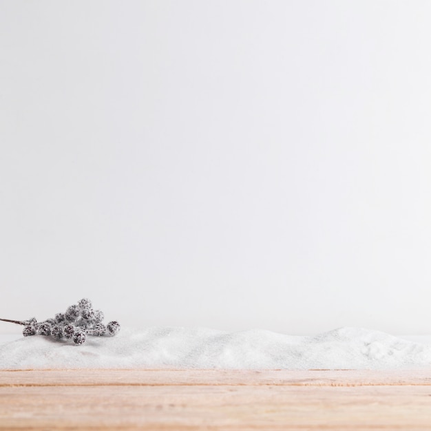 Foto gratuita tavola di legno vicino al ramoscello della pianta su mucchio di neve