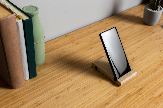 黒いスマートフォンと本の木製デスク