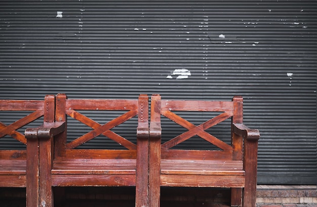 Wooden armchairs against the background of roller shutters near the cafe copy space Outdoor cafe in the rainy season interior design idea