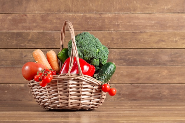 Wooden background with basket full of vegetables