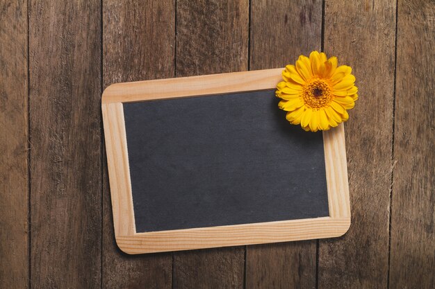 Wooden background with blackboard and decorative flower