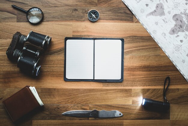 Wooden background with blank notebook and objects around