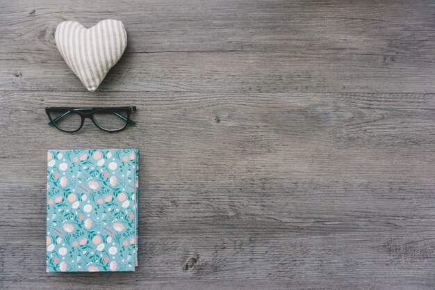 Wooden background with book, glasses and heart