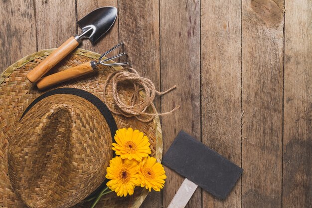 Wooden background with gardening tools and yellow flowers
