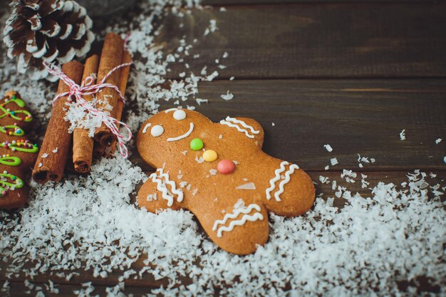 Wooden background with gingerbread man cones snow top view closeup