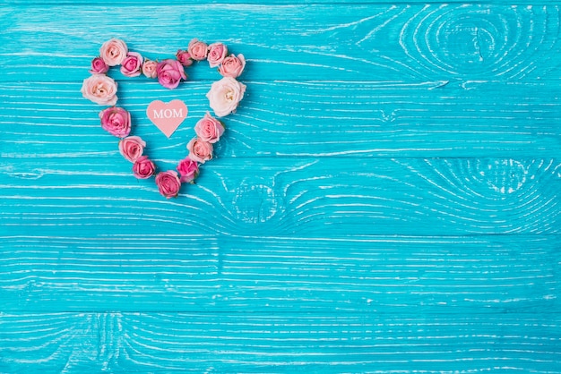 Wooden background with heart made of pink flowers for mother's day