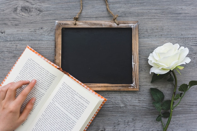 Wooden background with open book, slate and flower