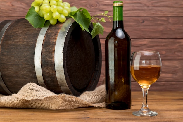 Free photo wooden barrel with bottle and glass of wine