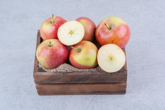 A wooden basket full of apples on white