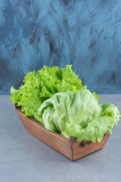 Wooden basket full of lettuce leaves. 