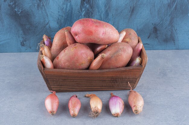 Бесплатное фото Деревянная корзина, полная красного картофеля и лука.