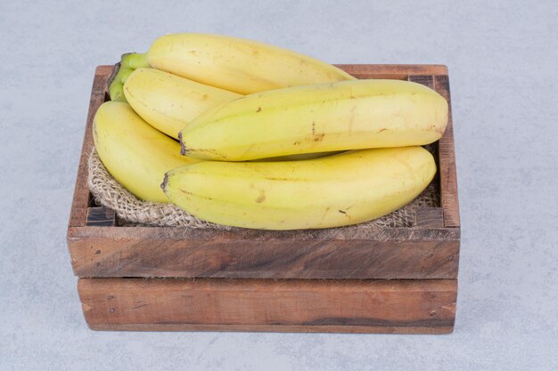 白い背景の上の熟したフルーツバナナでいっぱいの木製バスケット。高品質の写真