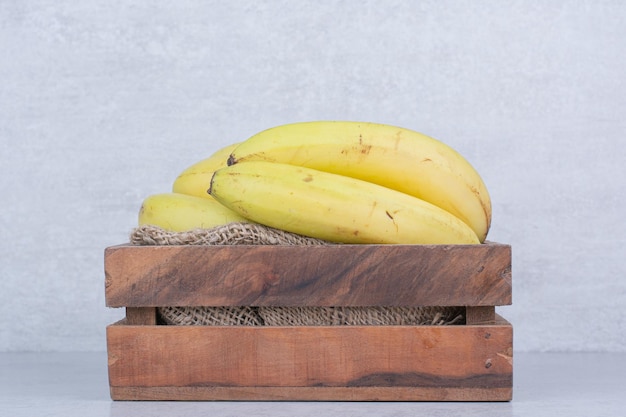 A wooden basket full of ripe fruit bananas on white