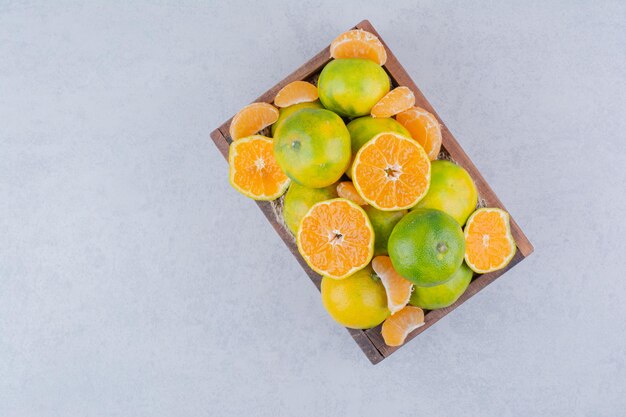 A wooden basket full of sliced tangerines on white background . High quality photo
