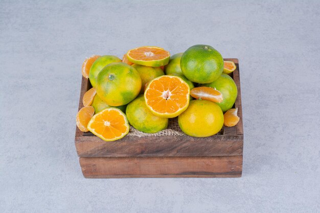 A wooden basket full of sliced tangerines on white background . High quality photo