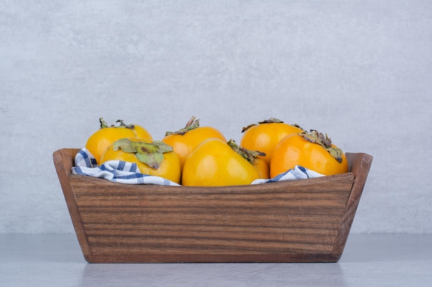 Free photo a wooden basket full of sweet persimmons on white background. high quality photo
