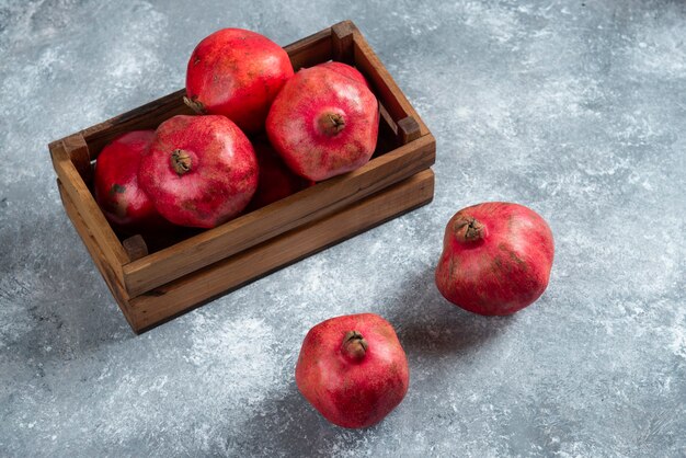 A wooden basket full of sweet ripe pomegranate fruits.