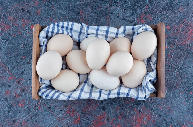 A wooden basket with fresh raw chicken eggs .