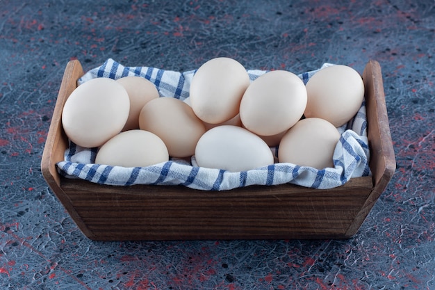 A wooden basket with fresh raw chicken eggs 