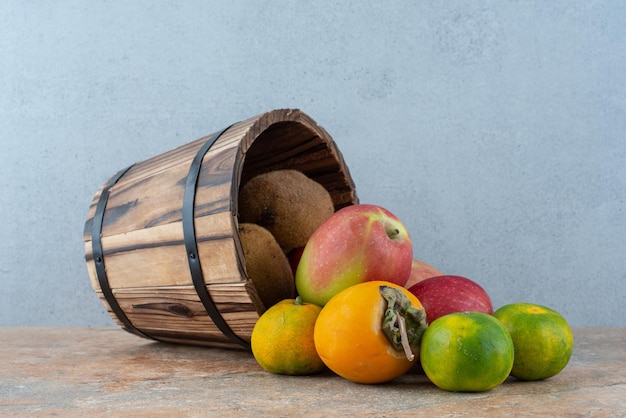 A wooden basket with fresh sweet fruits on gray