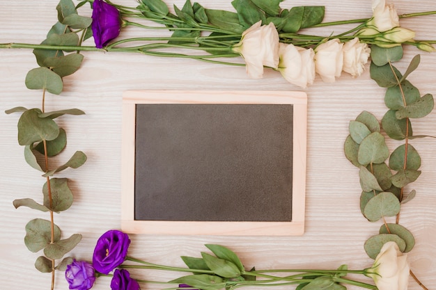 Ardesia in bianco di legno decorata con i fiori di eustoma su fondo di legno