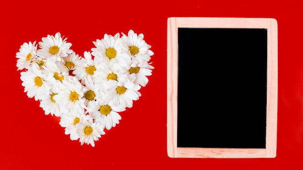 Бесплатное фото Деревянная доска и цветы ромашки в форме сердца