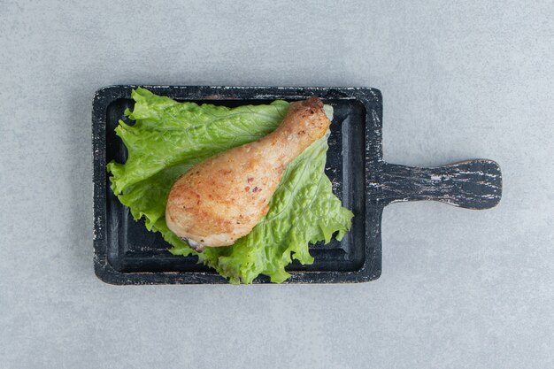 A wooden board of chicken fried leg with lettuce . 