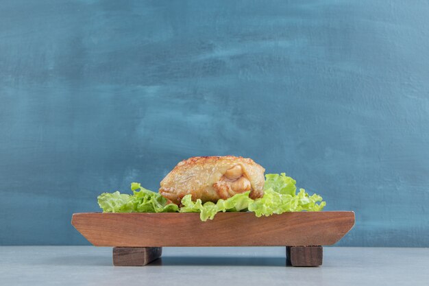 A wooden board of chicken fried meat with lettuce . 