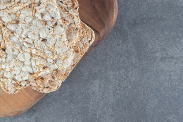 A wooden board of crispy square rice waffles.