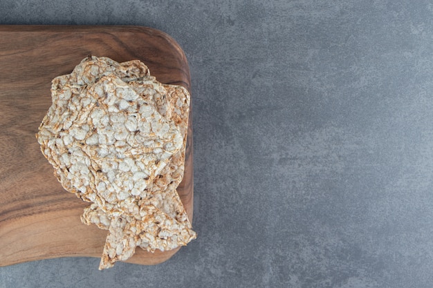 Free photo a wooden board of crispy square rice waffles.