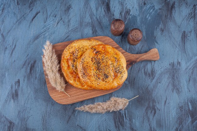 Wooden board of delicious fragrant pastries on marble background. 