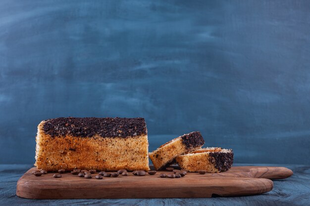 Wooden board of delicious sponge cake on marble background. 