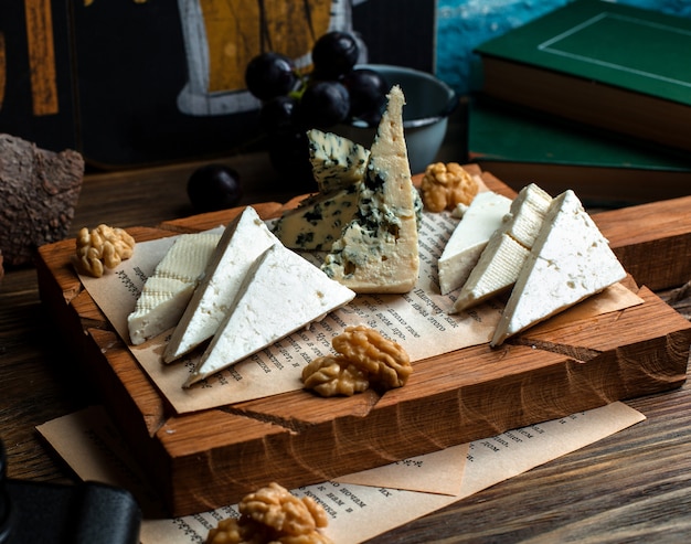 Wooden board of different cheeses and walnuts