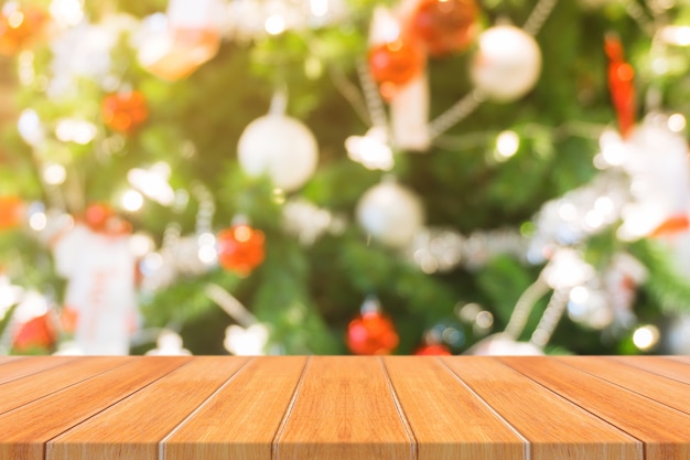 Wooden board empty table top on of blurred background. perspective brown wood table over blur christmas tree and fireplace background, can be used mock up for montage products display or design layout