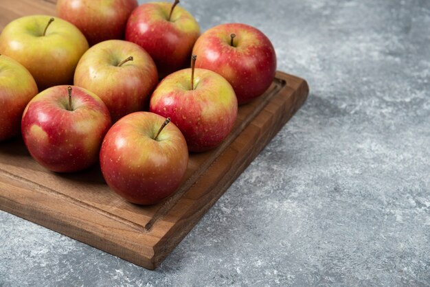 Tavola di legno di mele fresche deliziose sulla superficie di marmo.