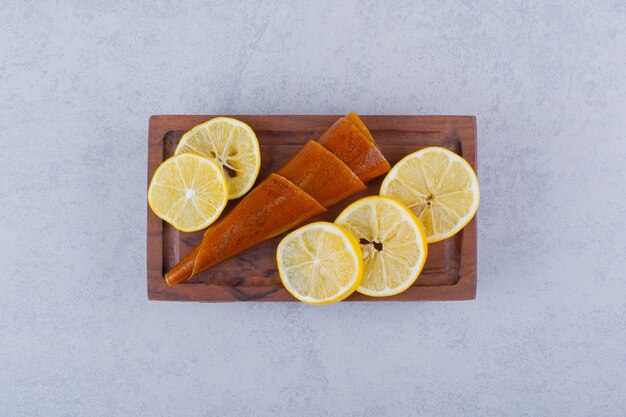 Wooden board of fresh juicy lemons and dry fruit rolls and on stone table. 