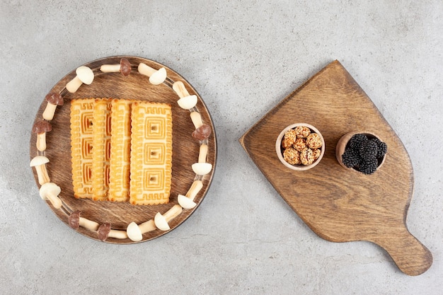 Free photo a wooden board full of biscuits and sweet mushrooms.