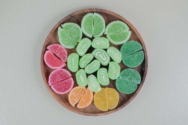 A wooden board full of colorful sugary marmalades .