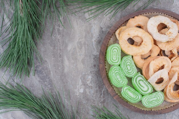 A wooden board full of dried apples and sugar marmalade on marble background. 